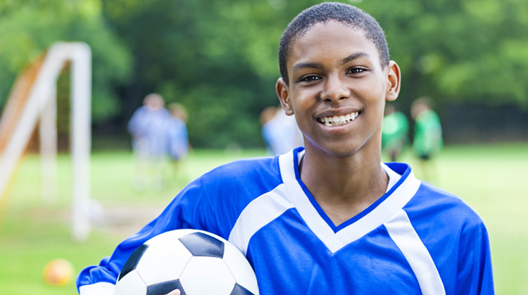 chico afroamericano sosteniendo un balón de futbol.