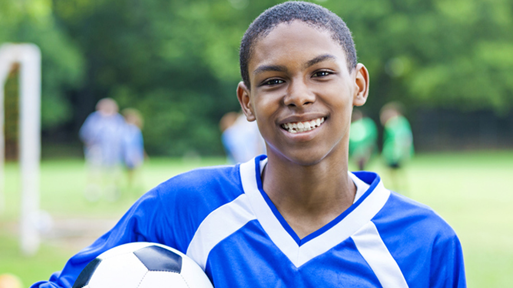 chico afroamericano sosteniendo un balón de futbol